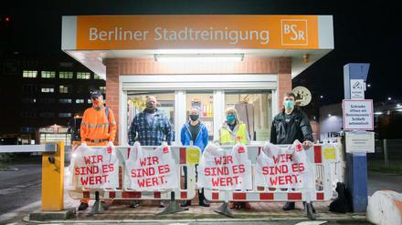 BSR-Beschäftigte und eine Verdi-Vertreterin stehen bei einem Warnstreik an der Zufahrt zum Reinigungshof Forckenbeckstraße.