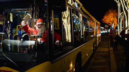 Ein als Weihnachtsmann verkleideter Busfahrer der Berliner Verkehrsbetriebe winkt in Berlin Passanten und Touristen von seinem Fahrerarbeitsplatz aus zu. 