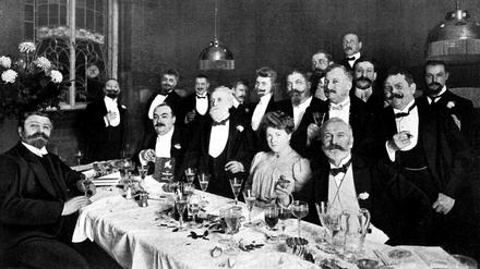 Eine festlich gekleidete Gesellschaft, bis auf die Frau des Gastgebers allesamt Herren, hat sich 1907 beim Hotelier Carl Kohlis versammelt. 