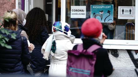 Menschen stehen in einer langen Schlange vor einer Arztpraxis im Bezirk Neukölln für einen Corona-Test an.