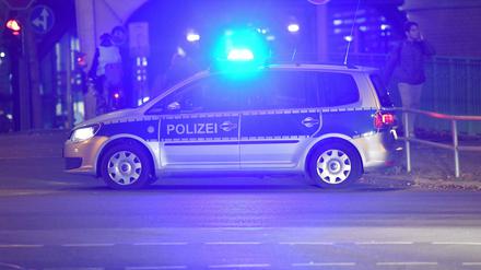 Ein Polizeiwagen steht in Berlin am frühen Abend quer zur Fahrbahn und blockiert die Straße.