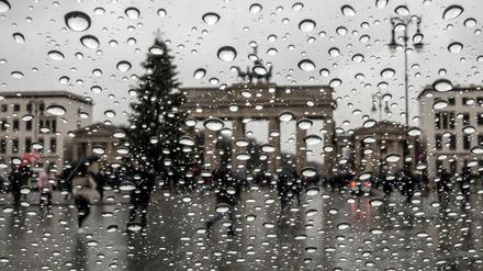Viel zu warm für Schnee: Das Brandenburger Tor und ein Weihnachtsbaum stehen hinter der Scheibe eines Autofensters auf dem Regentropfen hängen.