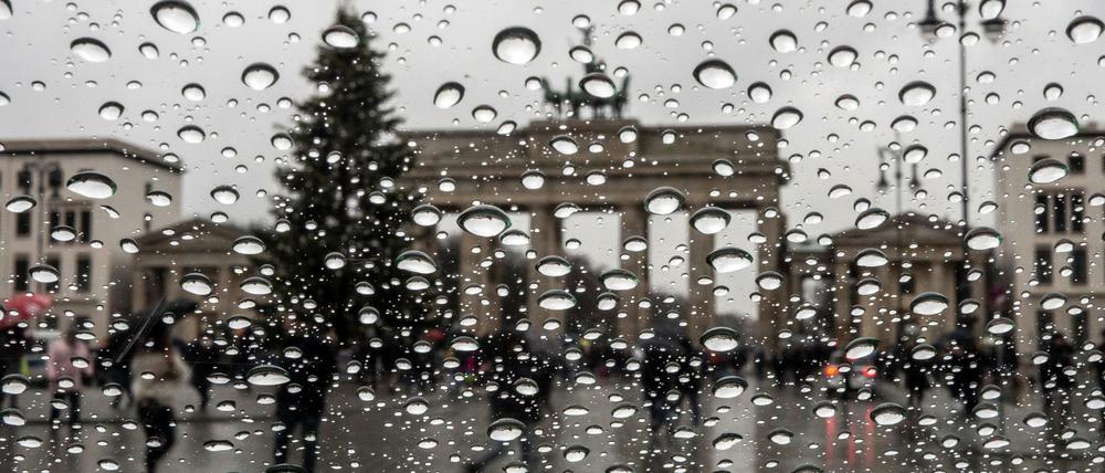 Viel zu warm für Schnee: Das Brandenburger Tor und ein Weihnachtsbaum stehen hinter der Scheibe eines Autofensters auf dem Regentropfen hängen.