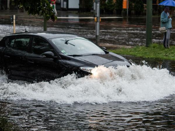Ein Pkw fährt nach einem Gewitter und starken Regenfällen durch die Wassermassen in der Breiten Straße. 