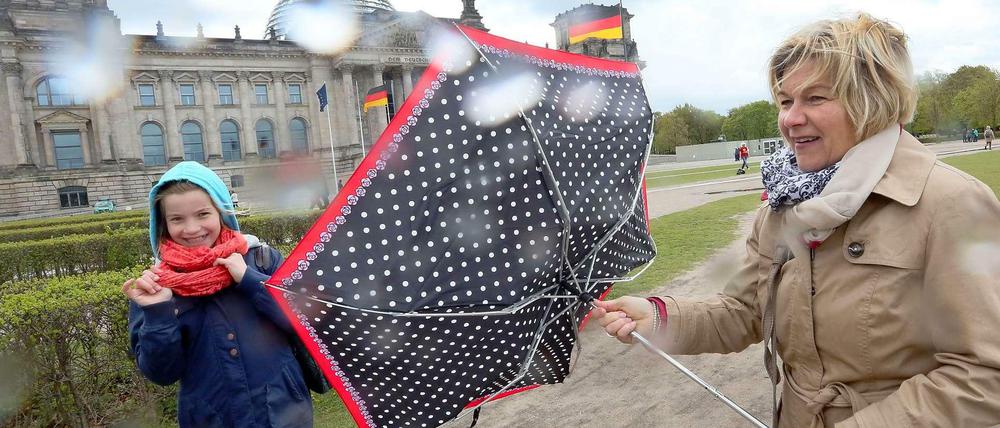 Bei dem Wind, half kein Schirm gegen die Regenschauer. Berlin-Besucher kämpften am Montag am Reichstag mit den Windböen.
