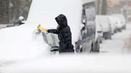 Bei Schneeregen befreit diese Frau ihr Auto von den Schneemassen. 