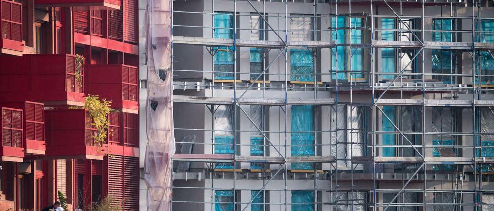 Ein Baugerüst steht an einem Rohbau neben bereits fertiggestellten Neubau-Wohnungen in Kreuzberg. 