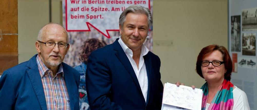 Berlins Regierender Bürgermeister Klaus Wowereit (SPD, M) überreicht im Sportmuseum Unterschriften der Spieler der deutschen Fußball-Nationalmannschafts an die Museumsleiterin Martina Behrendt. Der Mann links heißt Horst Milde und ist der Gründer des Berlin-Marathon.