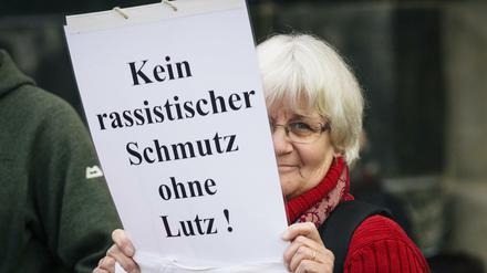 Die Menschenrechts-Aktivistin Irmela Mensah-Schramm steht mit einem Schild neben der Pegida-Kundgebung in Dresden.