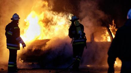Feuerwehrmänner der Berliner Feuerwehr löschen ein brennendes Auto (Symbolbild).