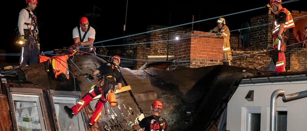 Feuerwehrleute entfernen auf dem Haus in Gesundbrunnen Dachpappe, welche durch ein Unwetter abgelöst wurde.