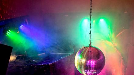 Eine Diskokugel dreht sich in einem Club und reflektiert das einfallende Licht der Scheinwerfer und Lampen. (Archivbild) 