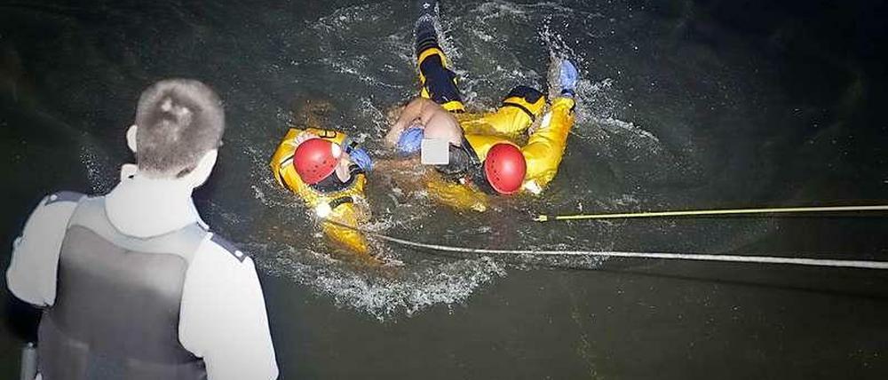 Zwei Feuerwehrleute holen den Schwimmer aus dem Wasser.
