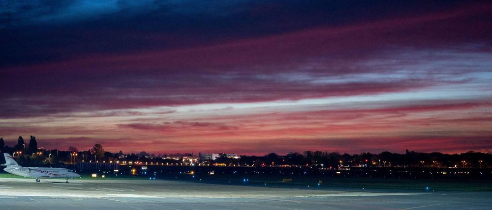 Ein Flugzeug steht im Mondlicht kurz vor dem Sonnenaufgang auf dem Flughafen Berlin Tegel.