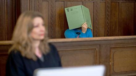 Im Gerichtssaal: Der Angeklagte verdeckt sein Gesicht mit einem Aktenhelfer. Vor ihm, seine Anwältin Julia Hilterscheid.