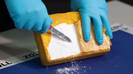 Ein Zollbeamter öffnet ein Paket mit Kokain.