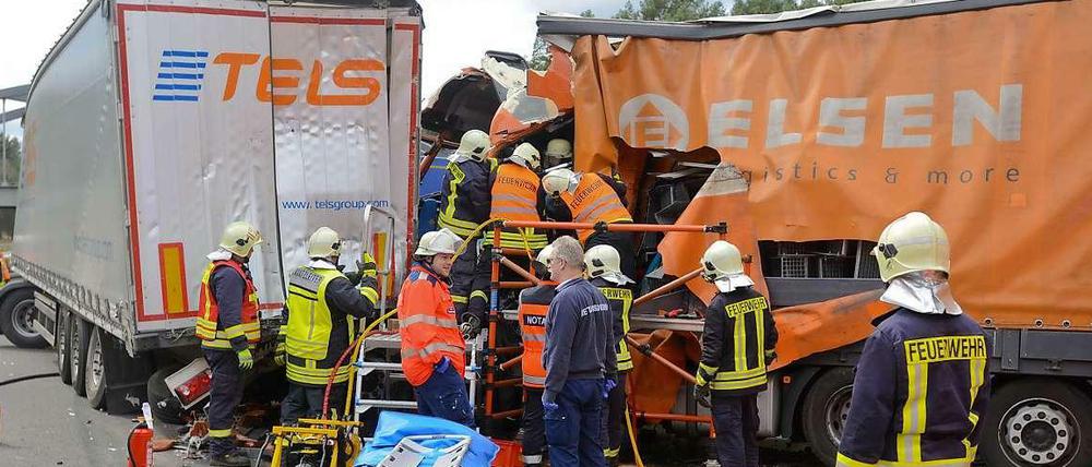 Feuerwehrleute und Rettungskräfte versuchen nach einem Unfall auf dem südlichen Berliner Ring bei Michendorf (Brandenburg) einen LKW-Fahrer aus dem Fahrerhaus zu befreien. 