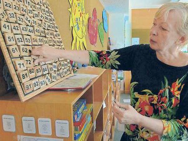 Schulleiterin Ilona Bernsdorf zeigt ein Holz-Rechenspiel, das Kinder in einer Schülerfirma selbst hergestellt haben. 