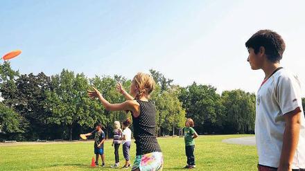 Mädchen und Jungen der Charlotte-Salomon-Schule spielen gemeinsam Frisbee im Sportunterricht.