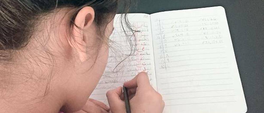 Zweisprachig schreiben. Ein Mädchen im Arabisch-Unterricht. 