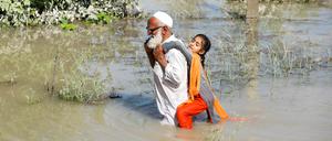 A man wades through flood waters carrying his grand daughter on his back following rains and floods during the monsoon season in Charsadda, Pakistan August 28, 2022. REUTERS/Fayaz Aziz