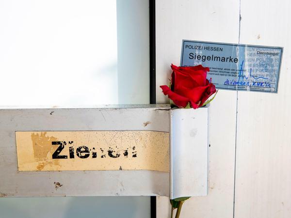 An einem Türgriff des Cafés, in dem zahlreiche Menschen starben, hat jemand eine Rose neben einem Siegel der Polizei angebracht.