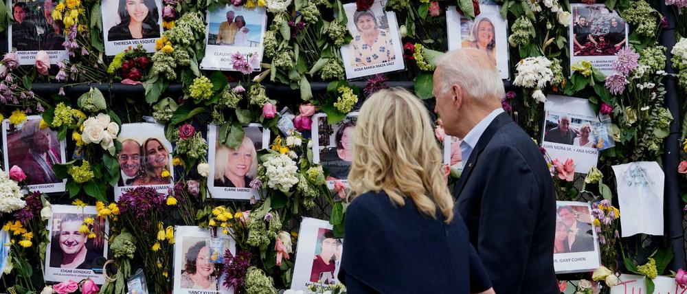 Joe und Jill Biden betrachten eine mit Blumen und Fotos der Vermissten bedeckte Gedenkwand.