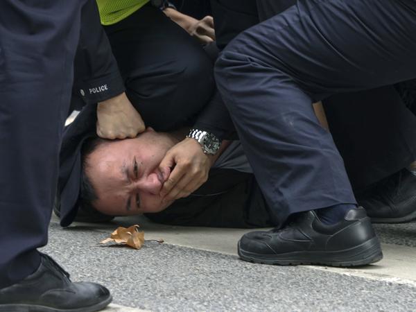 Polizisten halten einen Demonstranten in Shanghai fest. 