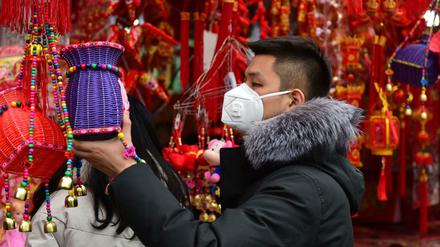 Ein Mann trägt eine Gesichtsmaske, während er auf einem Markt in Fuyang für das bevorstehende chinesische Neujahrsfest zum Jahr der Ratte einkauft. 