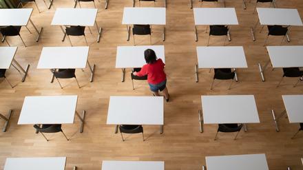 Eine Frau bereit in der Aula im Sorbischen Gymnasium Bautzen Tische und Stühle für die bevorstehenden Abschlussprüfungen vor.