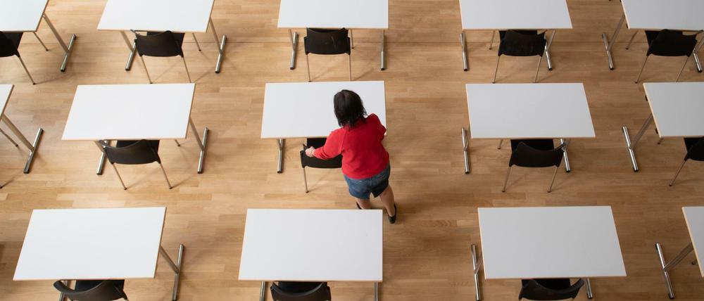 Eine Frau bereit in der Aula im Sorbischen Gymnasium Bautzen Tische und Stühle für die bevorstehenden Abschlussprüfungen vor.