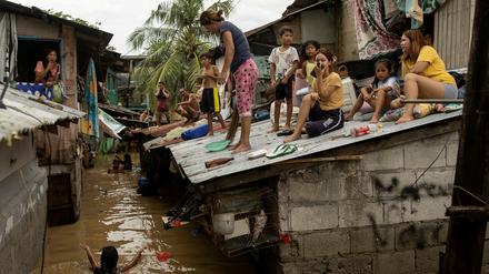 Menschen sitzen nach dem Taifun auf einem Häuserdach auf den Philippinen.     
