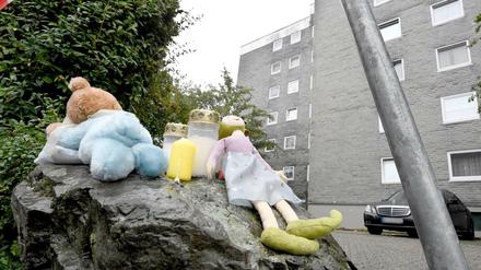 Eine Puppe und Kerzen liegen auf einem Felsen vor einem Wohnblock in Solingen.