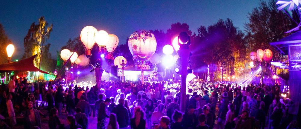 Festivalbesucher tanzen auf einer mit leuchtenden Ballonen geschmückten Bühne auf dem Gelände des Fusion-Festival 2019. 