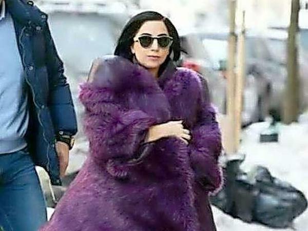 Lady Gaga wird auf der Straße fotografiert und trägt einen großen, lilanen Fellmantel