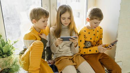 Drei Kinder mit Smartphone (Symbolbild).