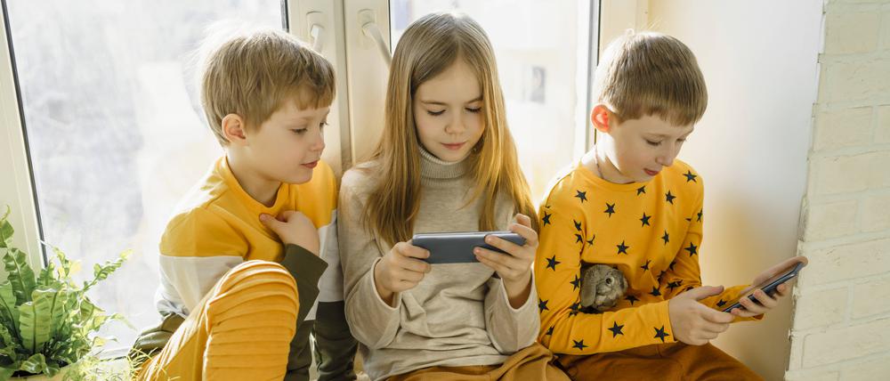 Drei Kinder mit Smartphone (Symbolbild).