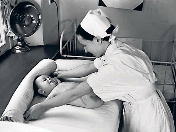 Auf der Kinderstation. Eine Krankenschwester mit Säugling, 1935.