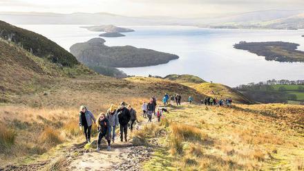 Familien wandern nahe dem Ort Balmaha den Conic Hill hinauf. Zur Belohnung gibt es einen Panoramablick auf Loch Lomond, Schottlands größten See.