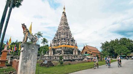 Auf einer Mountainbiketour radeln Touristen am Chedi Liam Temple in Chiang Mai vorbei. 