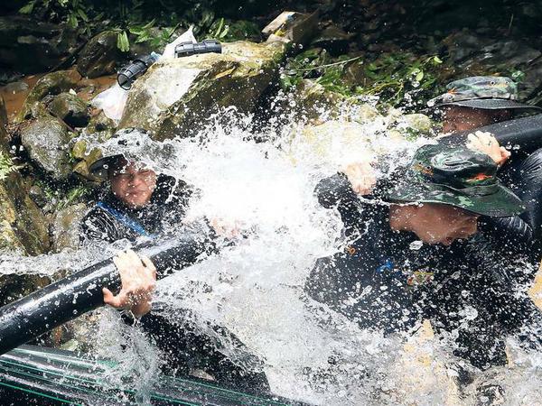 Soldaten des thailändischen Militärs legen Schläuche, damit Wasser abfließen kann.