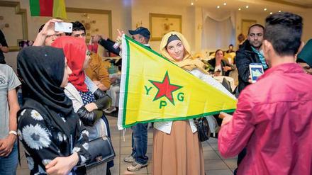 Waffenschwester. Auf einer Feier in Wedding schwenkt eine Kurdin die Fahne der Volksverteidigungseinheiten „YPG“, die in Syrien gegen Islamisten kämpfen.
