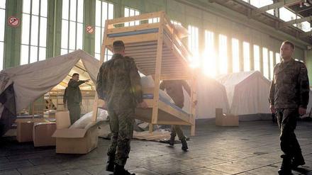 THW-Helfer und Bundeswehr-Soldaten richten gemeinsam eine Flüchtlingsunterkunft im alten Berliner Flughafen Tempelhof ein.