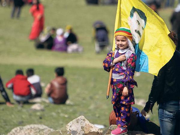 Vorbild im Stadtpark. Ein Mädchen schwenkt in Rojava eine Flagge mit dem in der Türkei inhaftierten PKK-Chef Abdullah Öcalan.