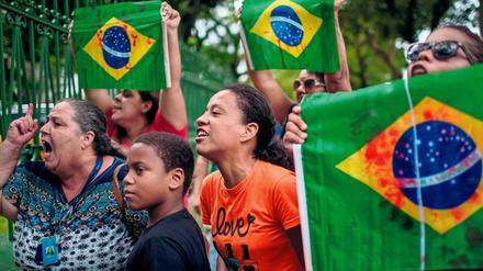 Bei der Beerdigung von Evaldo dos Santos Rosa zeigen Demonstranten eine brasilianische Flagge mit künstlichen Blutflecken. Soldaten hatten mehr als 80 Schüsse auf das Auto des Musikers abgegeben.