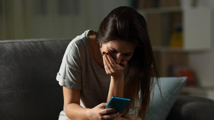 Sad teen receiving bad news online at home.