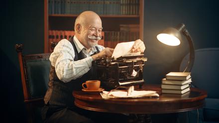 Ein Autor arbeitet an seiner Schreibmaschine an einem Manuskript.