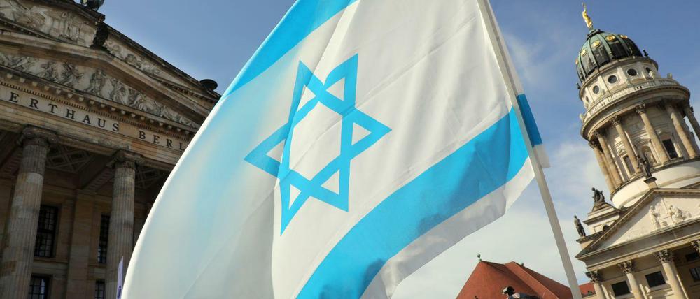 Mit einer israelischen Flagge gedenken Menschen 2018 auf dem Gendarmenmarkt der Unabhängigkeit Israels.