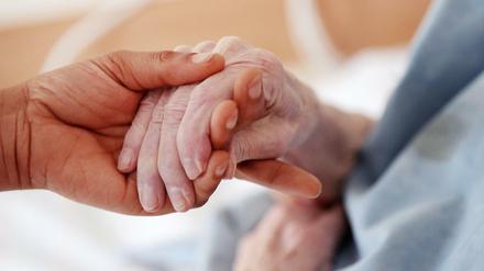 Eine Pflegerin hält die Hand einer Bewohnerin (Symbolbild).