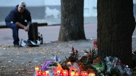 Ein Teilnehmer einer Kundgebung für einen verstorbenen 22-Jährigen sitzt auf einem Spielplatz neben Kerzen und Blumen. 